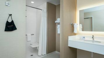 A modern bathroom with a white sink, mirror, and shower curtain.