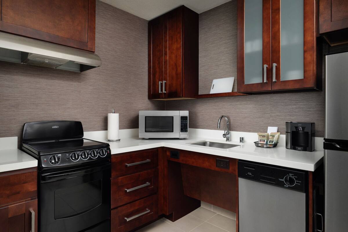 Una cucina moderna con mobili in legno, un frigorifero in acciaio inossidabile, un forno a microonde, un piano cottura e una lavastoviglie.