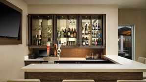 Eine moderne Küche mit Barbereich, ausgestattet mit einer großen Kochinsel, Barhocker und einem Weinkühlschrank.