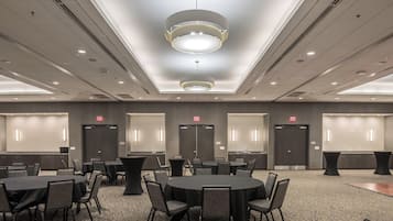 A conference room with round tables, chairs, and a modern ceiling light fixture.