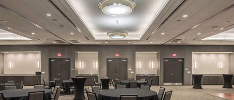 A conference room with round tables, chairs, and a modern ceiling light fixture.