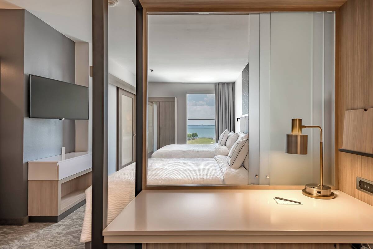 Une chambre d’hôtel moderne dotée d’un grand lit, d’un bureau, d’une télévision à écran plat et offrant une vue sur l’extérieur.