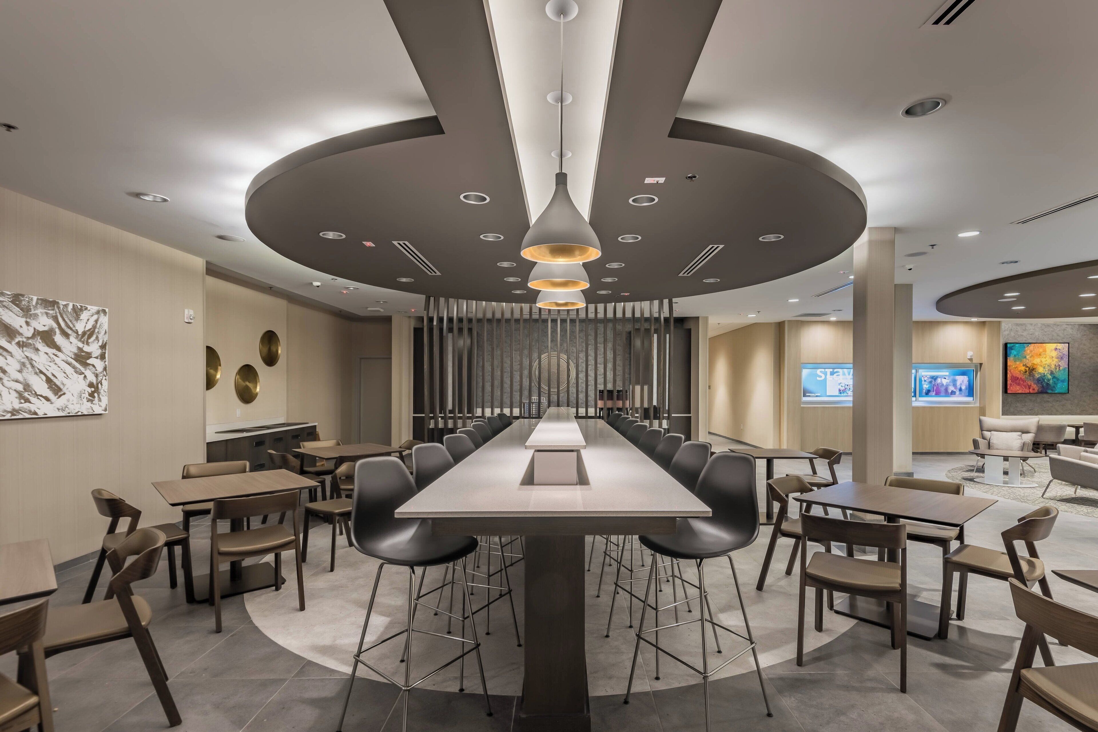 A modern conference room with a long table, black chairs, and a central chandelier.