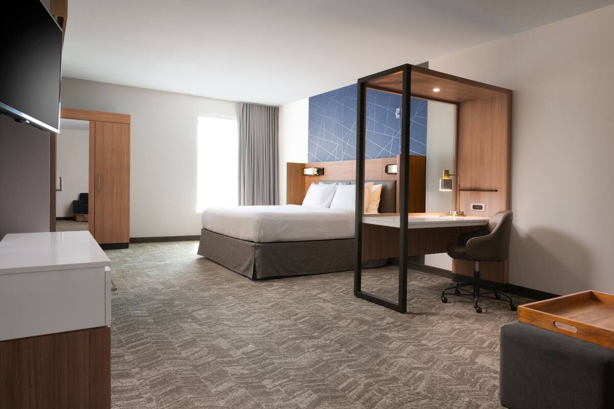 Une chambre d’hôtel avec un lit, un bureau, une chaise et un téléviseur.