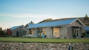 A modern house with a stone facade, large windows, and a blue roof. - Mt Michael Lodge (Lowburn)
