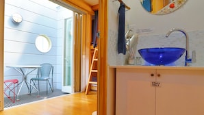 Une cuisine compacte avec un évier en céramique bleu, un panneau indiquant « personnel seulement », et un petit coin repas comprenant deux chaises et une table.