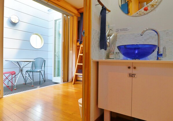 Une cuisine compacte avec un évier en céramique bleu, un panneau indiquant « personnel seulement », et un petit coin repas comprenant deux chaises et une table.
