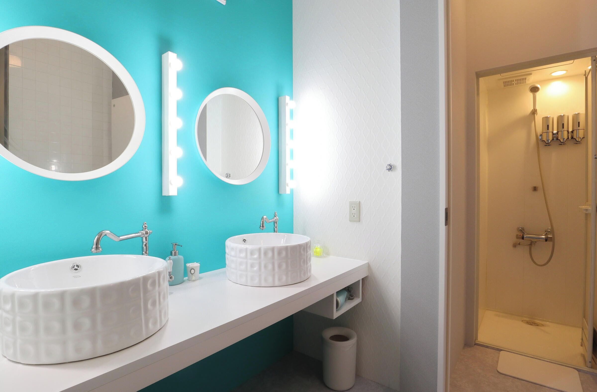 A bathroom with two sinks, a mirror, and a shower.