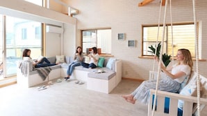 Un salon moderne avec un canapé blanc, un fauteuil suspendu et une grande fenêtre.