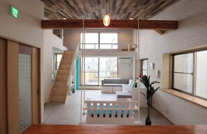 Un intérieur moderne avec un escalier en bois, un coin salon et de grandes fenêtres.