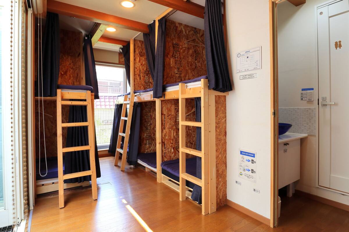 Une chambre de dortoir avec des lits superposés, une petite kitchenette et une porte avec une pancarte.
