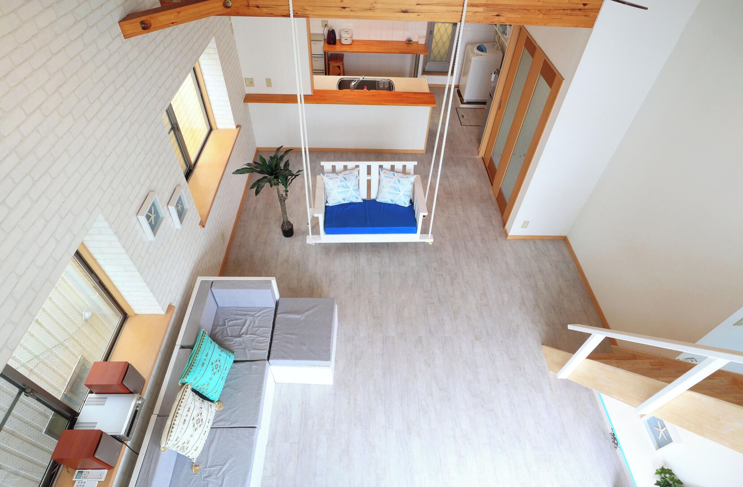 A multi-level interior with a suspended bed, a sofa, and a small kitchen area.