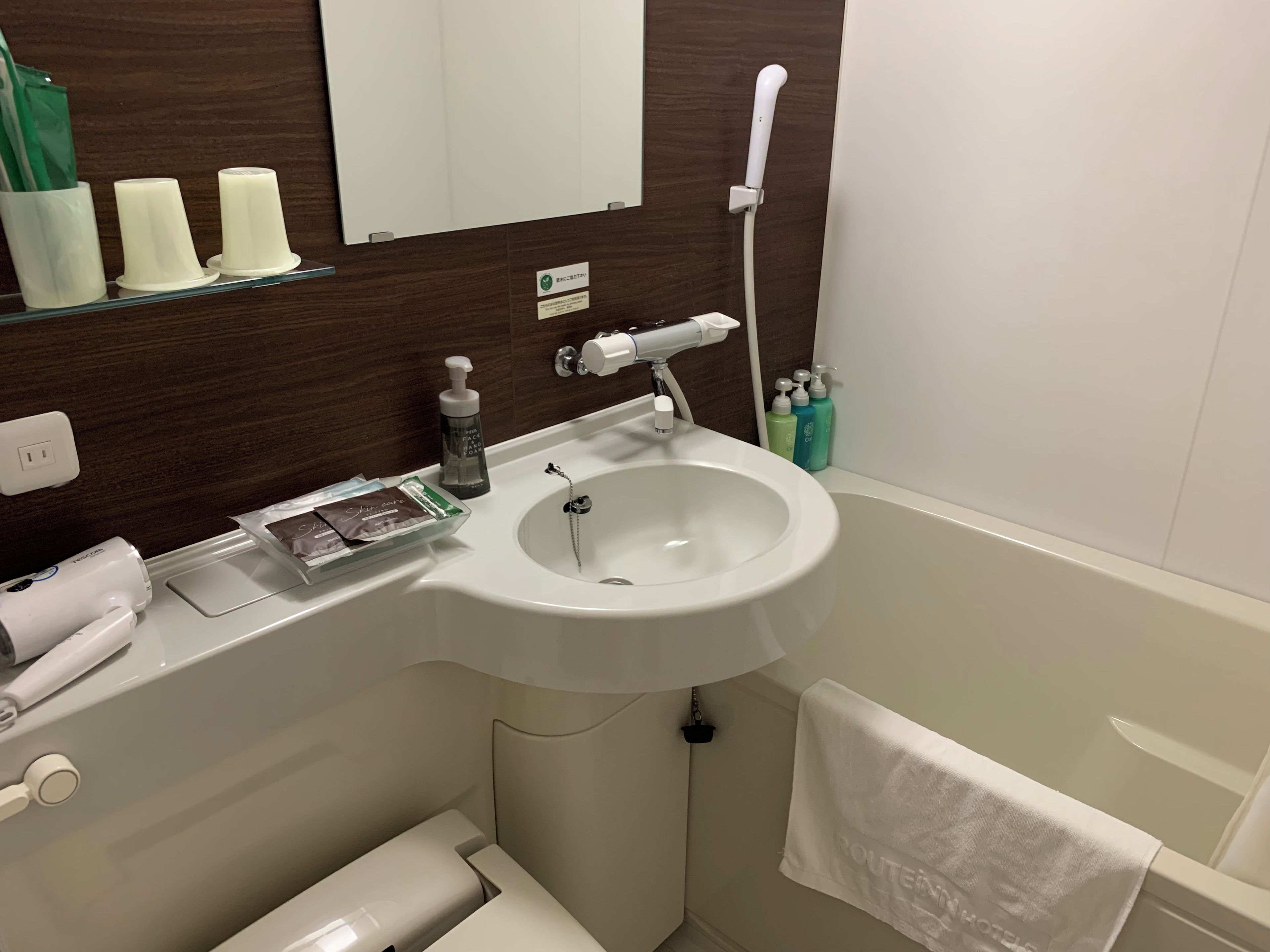 A bathroom with a white sink, a mirror, a towel rack, and toiletries.