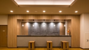 A reception area with a wooden counter, three pendant lights, and two wooden stools. - Hotel Route Inn Isesaki Inter (Isesaki)