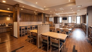 A spacious restaurant with wooden tables and chairs, a counter area, and a high ceiling with recessed lighting. - Hotel Route Inn Isesaki Inter (Isesaki)