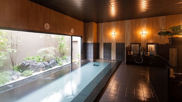 A modern spa with a glass-enclosed hot tub, wooden paneling, and a view of a garden. - Hotel Route Inn Isesaki Inter (Isesaki)