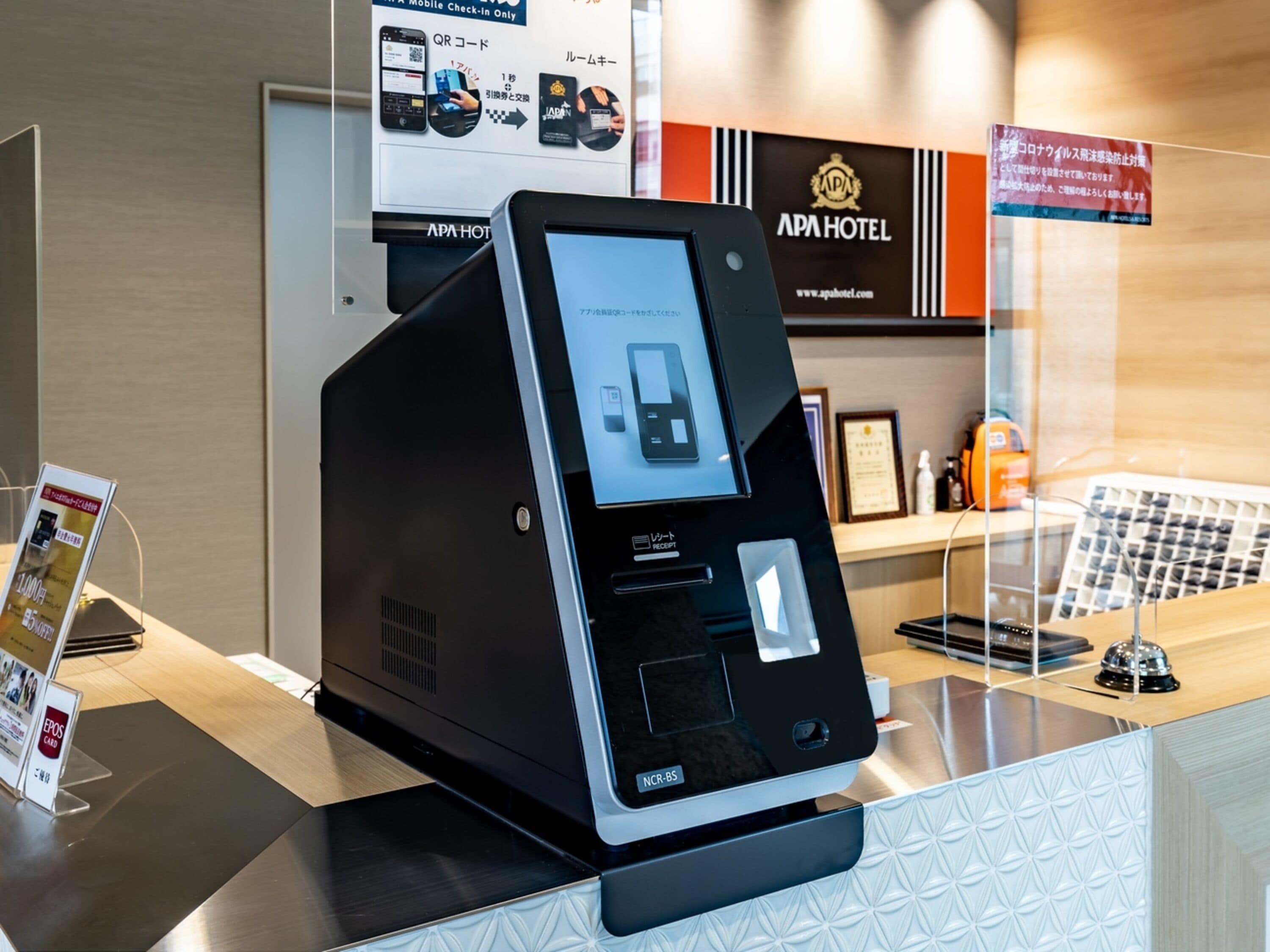 A self-service kiosk with a touchscreen interface, a receipt printer, and a card reader.