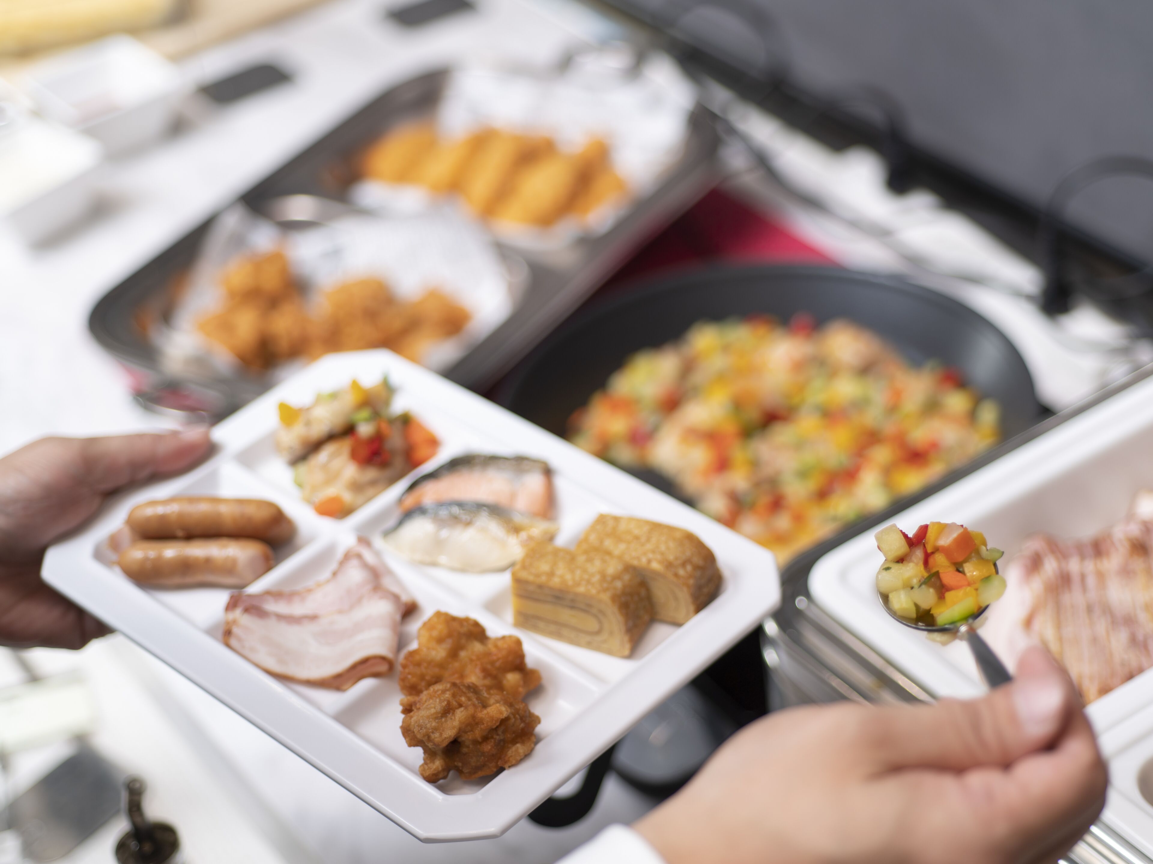 A buffet spread with various dishes including fried items, meats, and a fruit salad.