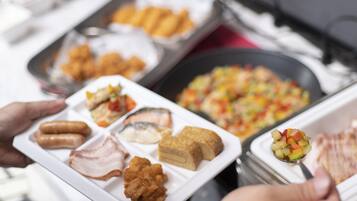 A buffet spread with various dishes including fried items, meats, and a fruit salad.
