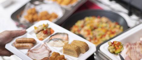 A buffet spread with various dishes including fried items, meats, and a fruit salad.
