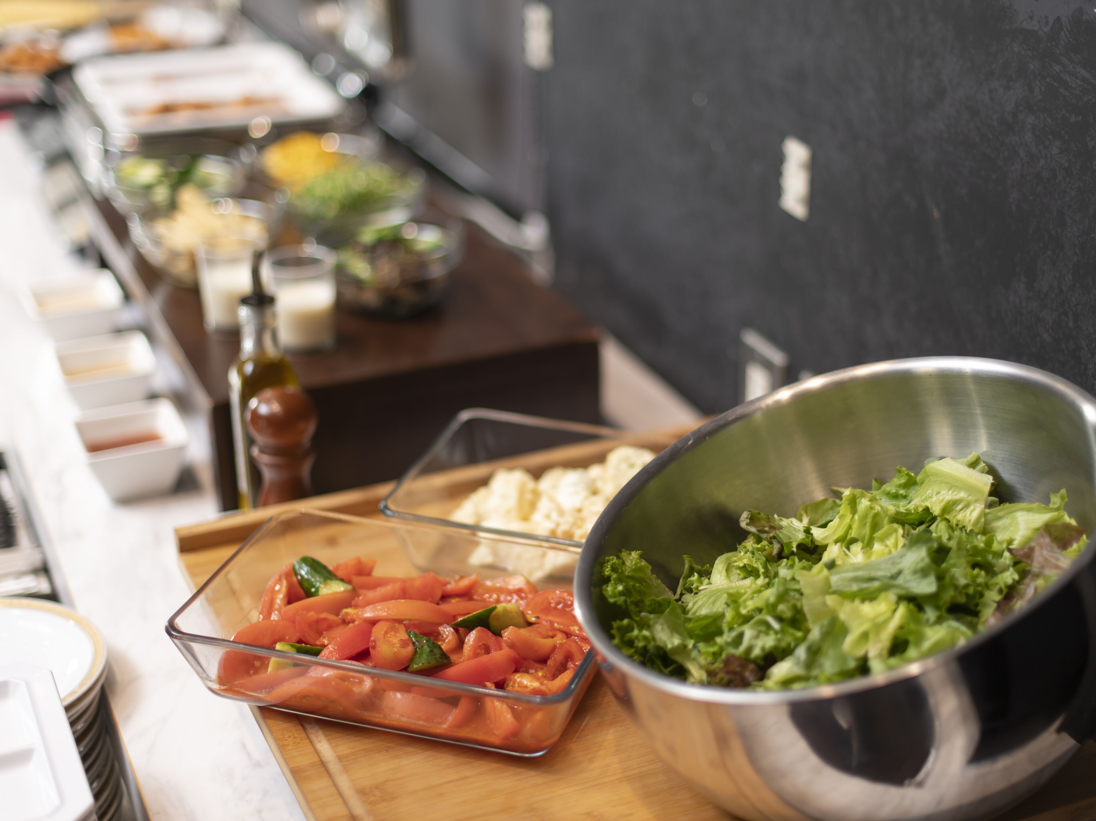 A buffet with various food items including a bowl of salad and a tray of sliced tomatoes.