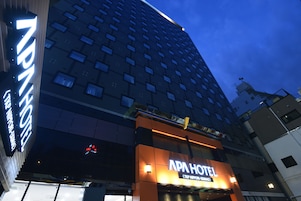 A hotel with a modern facade, multiple floors, and a prominent sign for the APA HOTEL.