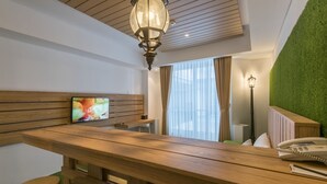Un'area della reception di un hotel con una scrivania in legno, una televisione a schermo piatto, un telefono e una parete verde.