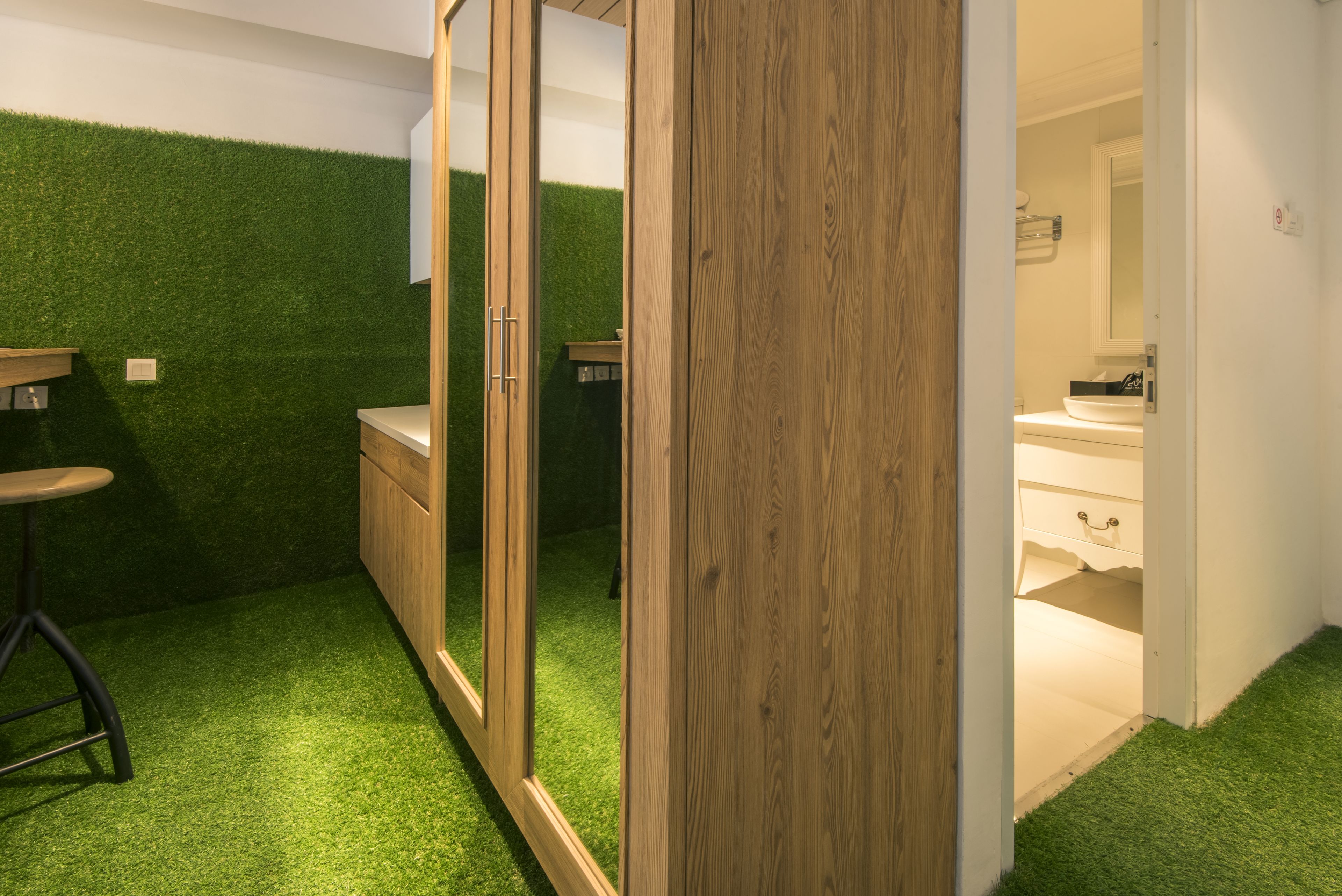 A bathroom with a wooden vanity, a mirror, and a green artificial grass floor.