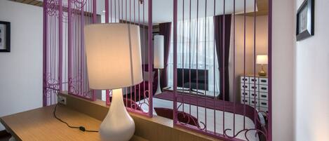 A room with a wooden desk, a white lamp, and a purple decorative partition.