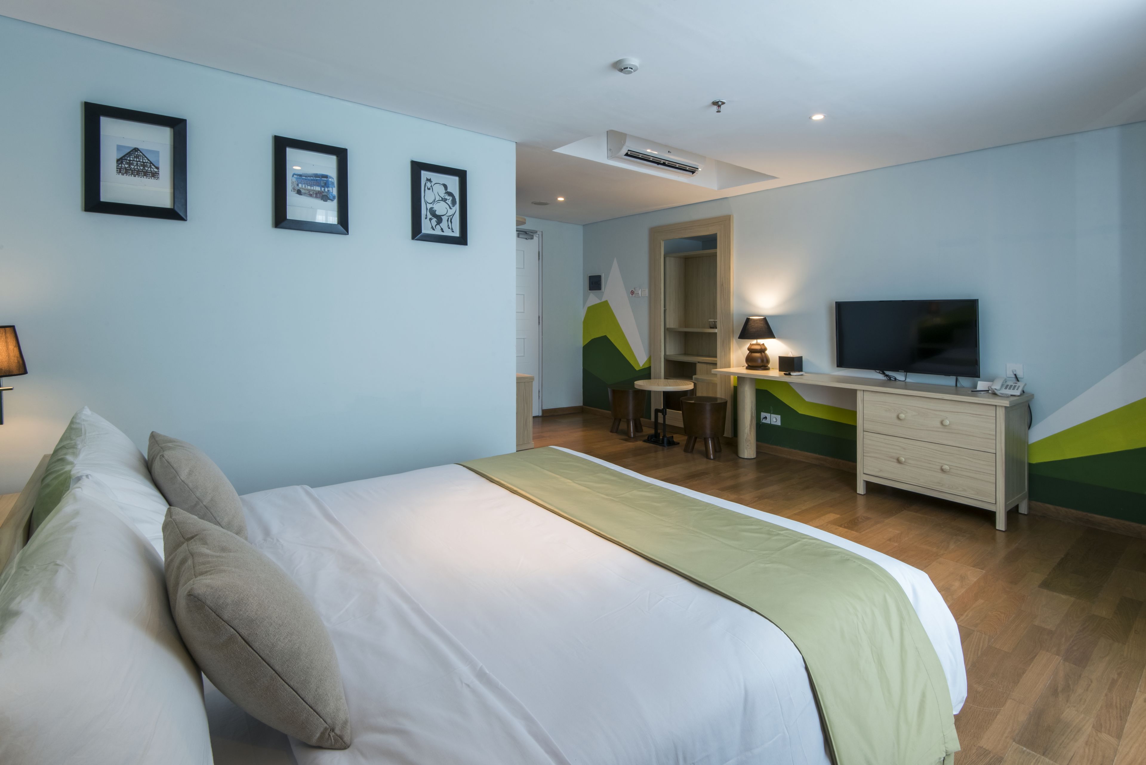 A hotel room with a bed, a desk, a television, and a wardrobe.
