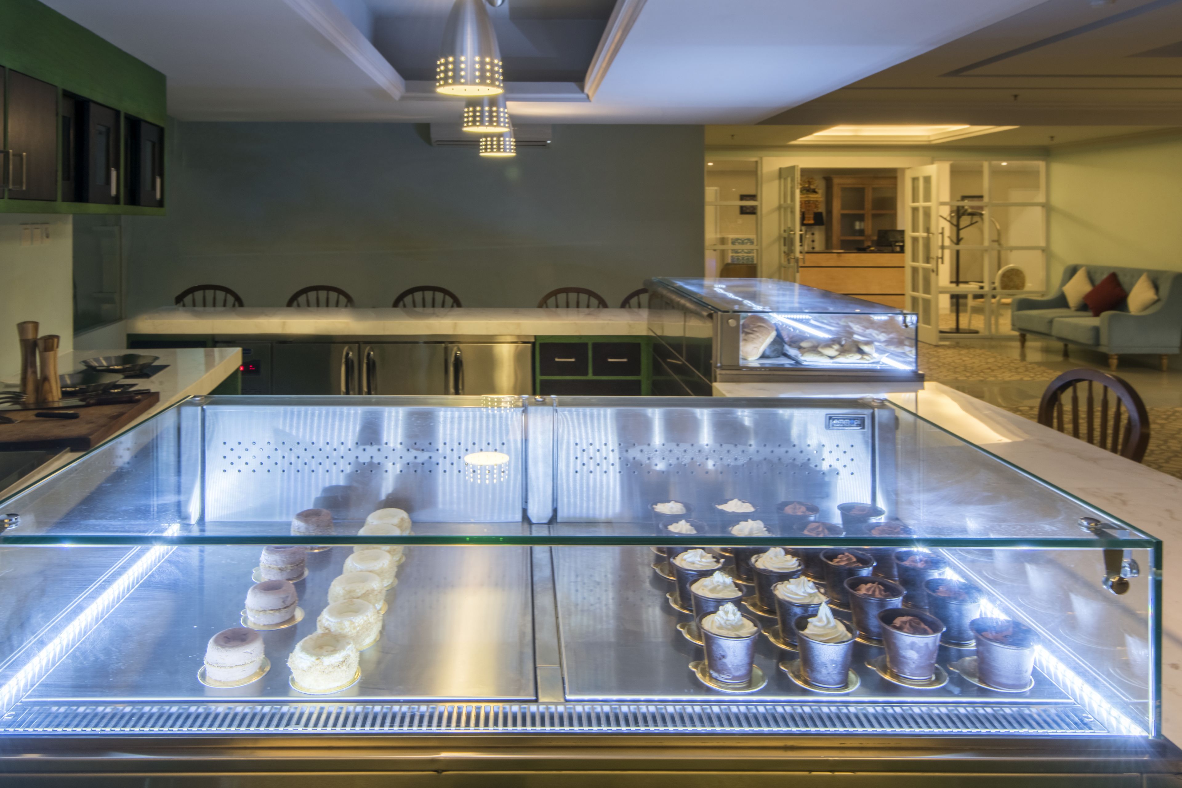 A bakery display case with pastries and a seating area with chairs and a table.