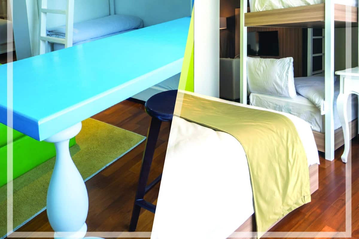 A hotel room with a bunk bed, a desk, and a chair.