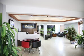 A reception area with a sign for Studio 2, a reception desk, a TV, and a seating area with chairs and a table. - V-studio Hotel Apartment 2 (Hanoi)