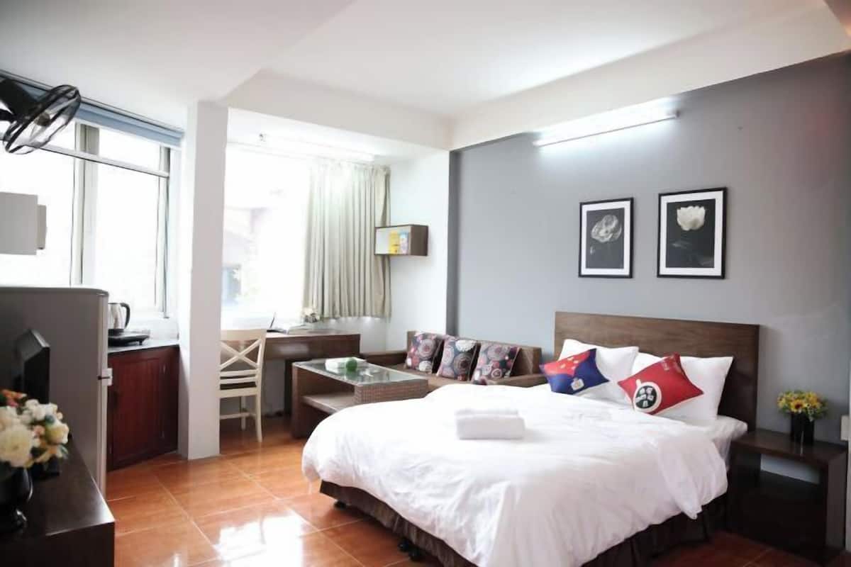 Habitación de hotel con cama, escritorio, silla y ventana.