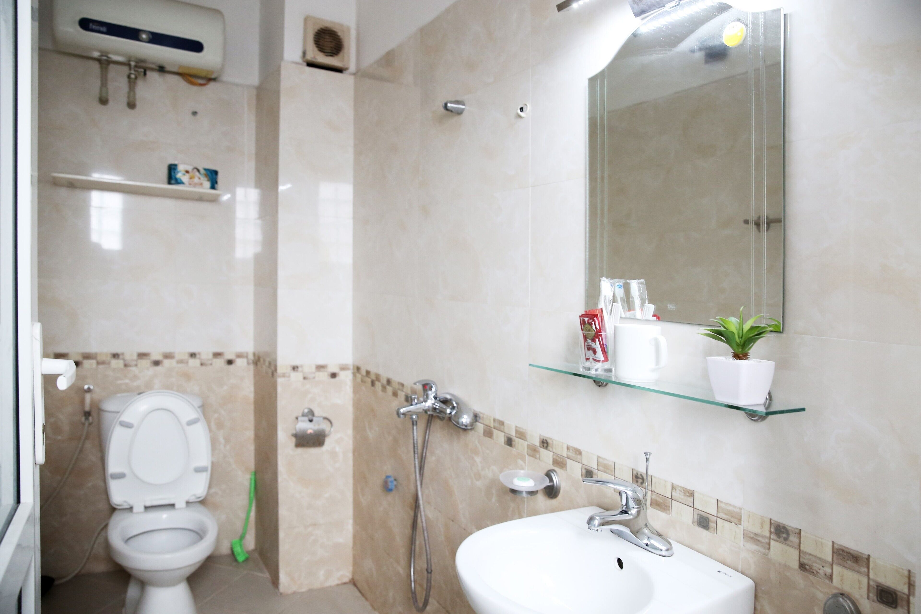 A bathroom with a toilet, a sink, a shower, and a mirror.