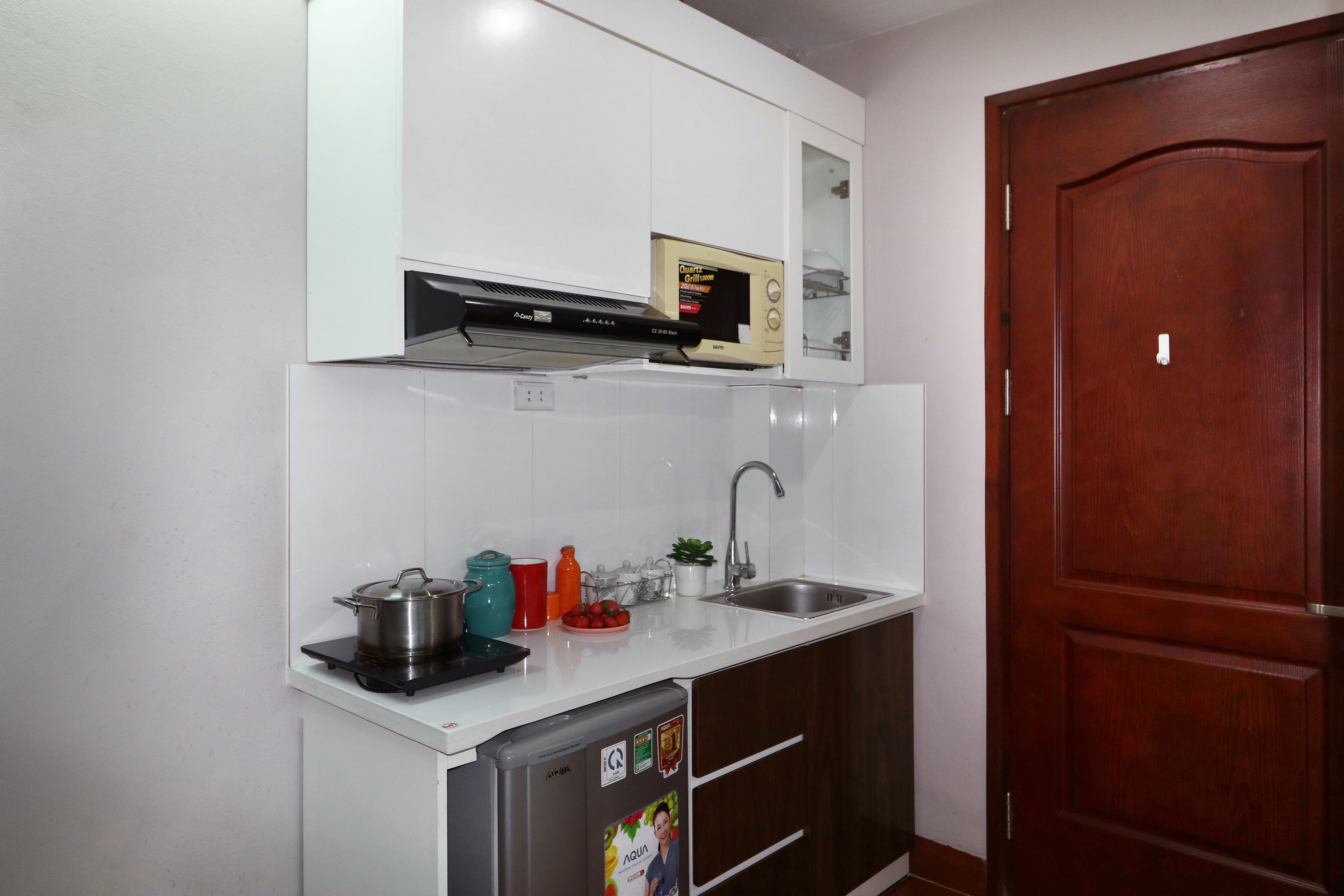 A compact kitchen with a microwave, sink, and a dishwasher.