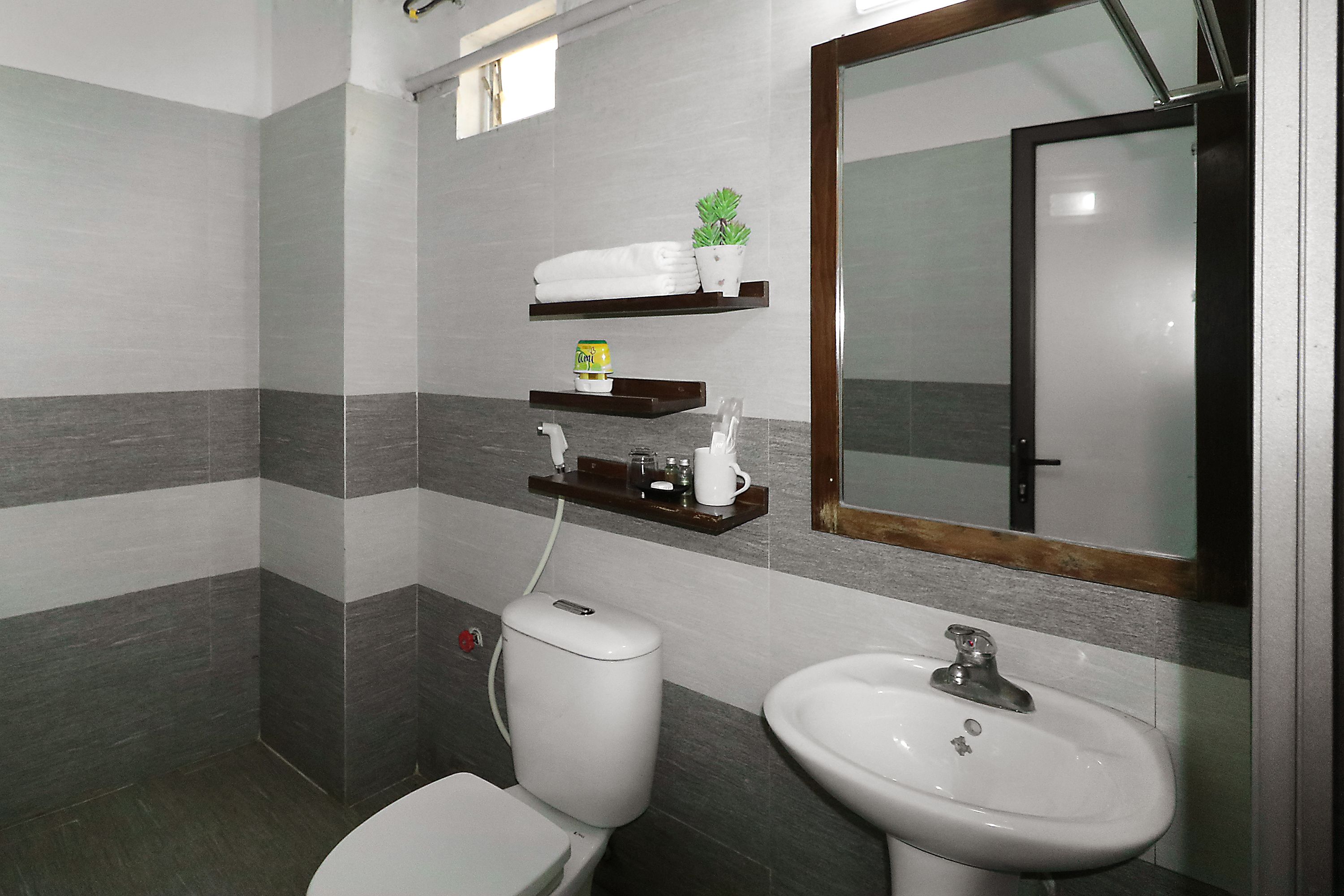 A bathroom with a toilet, sink, and shelves with toiletries.