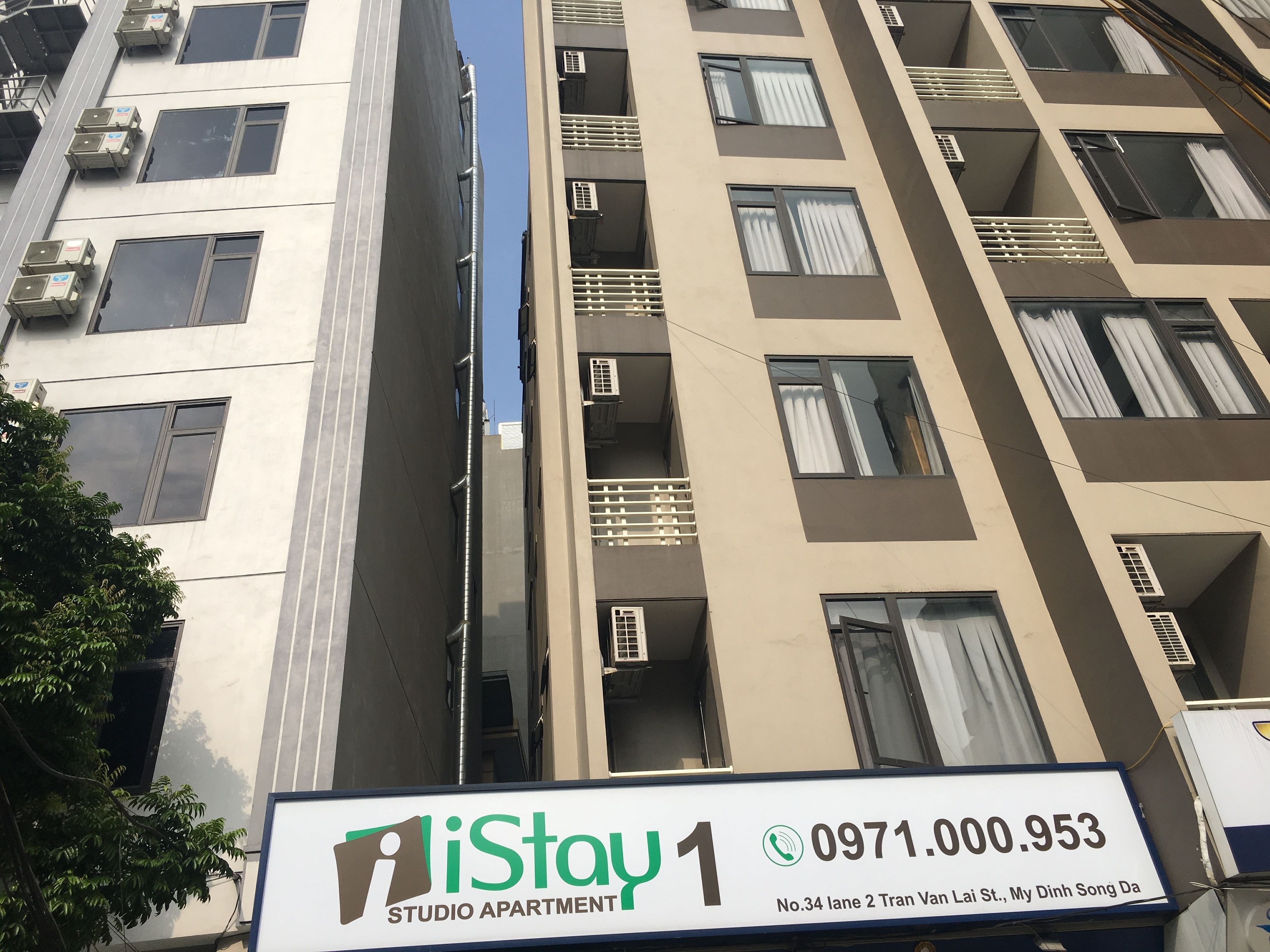 A multi-story building with a sign for 'iStay 1 Studio Apartment' at the bottom.