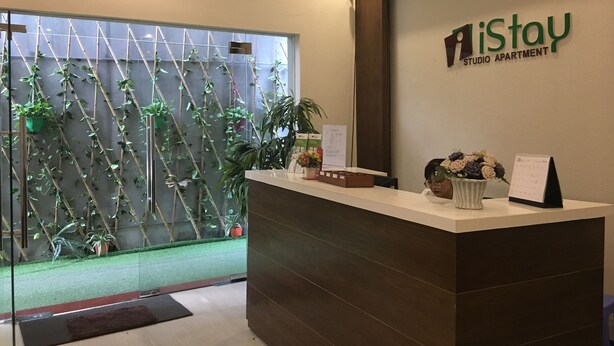 A reception desk with a 'iStay Studio Apartment' sign, a calendar, and a plant arrangement. - iStay Hotel Apartment 1 (Hanoi)