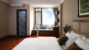 A hotel room with a large bed, a window with a view, a small table with a vase of flowers, and a door with patterned glass. - iStay Hotel Apartment 1 (Hanoi)