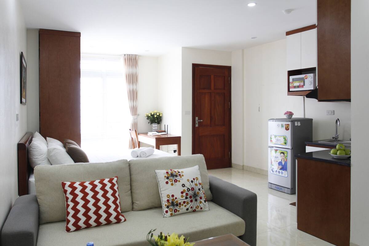 A compact living space with a sofa, a kitchenette, and a dining area.