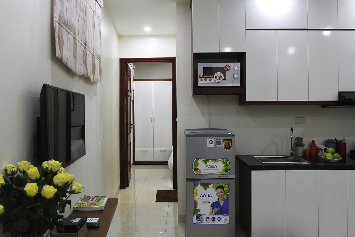 A modern kitchen with white cabinets, a microwave, and a refrigerator with water dispenser.