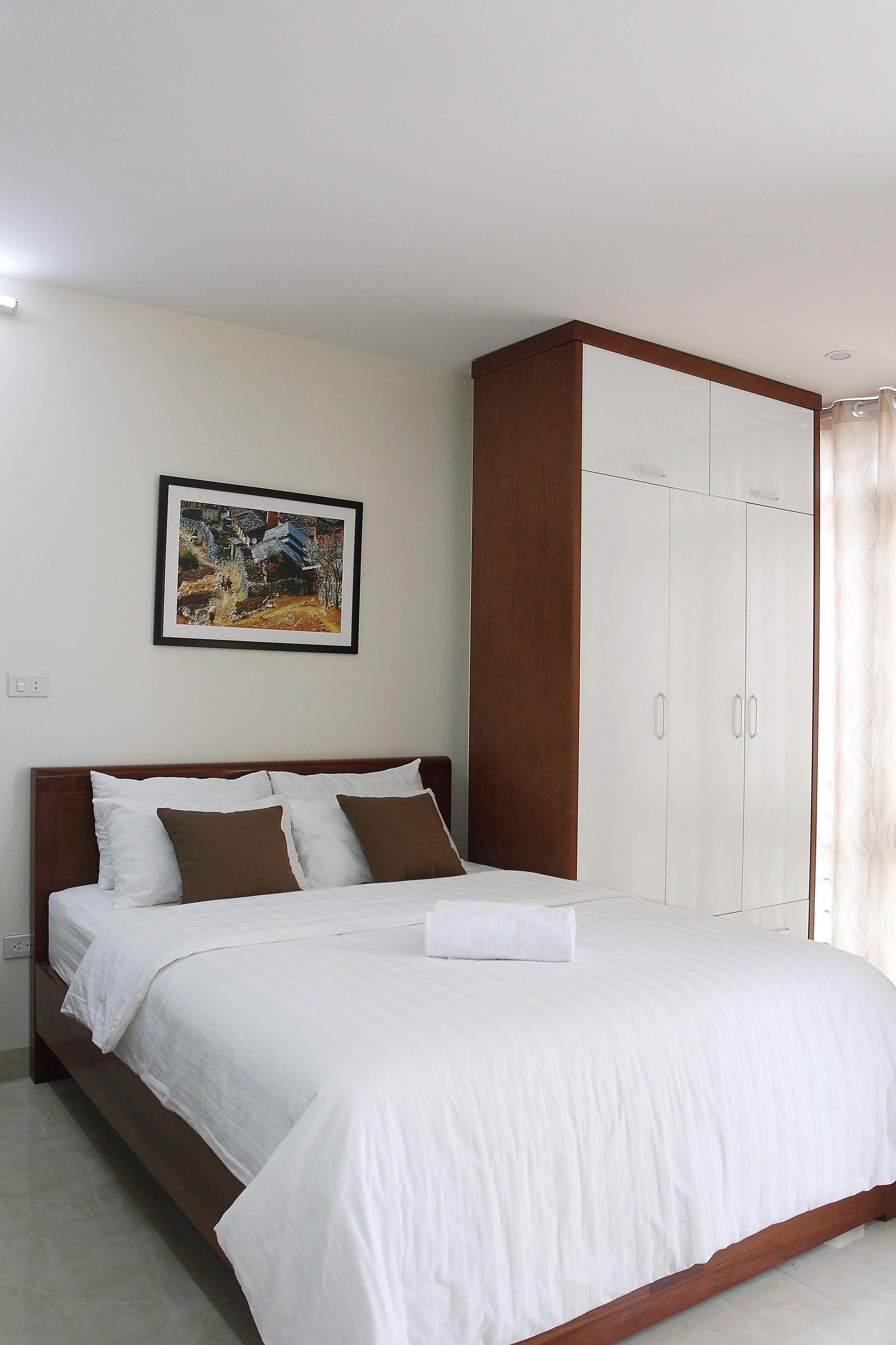 A bedroom with a bed, a wardrobe, and a framed picture on the wall.
