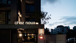 A hotel entrance with illuminated signage reading "chez nous" and a visible entrance door.