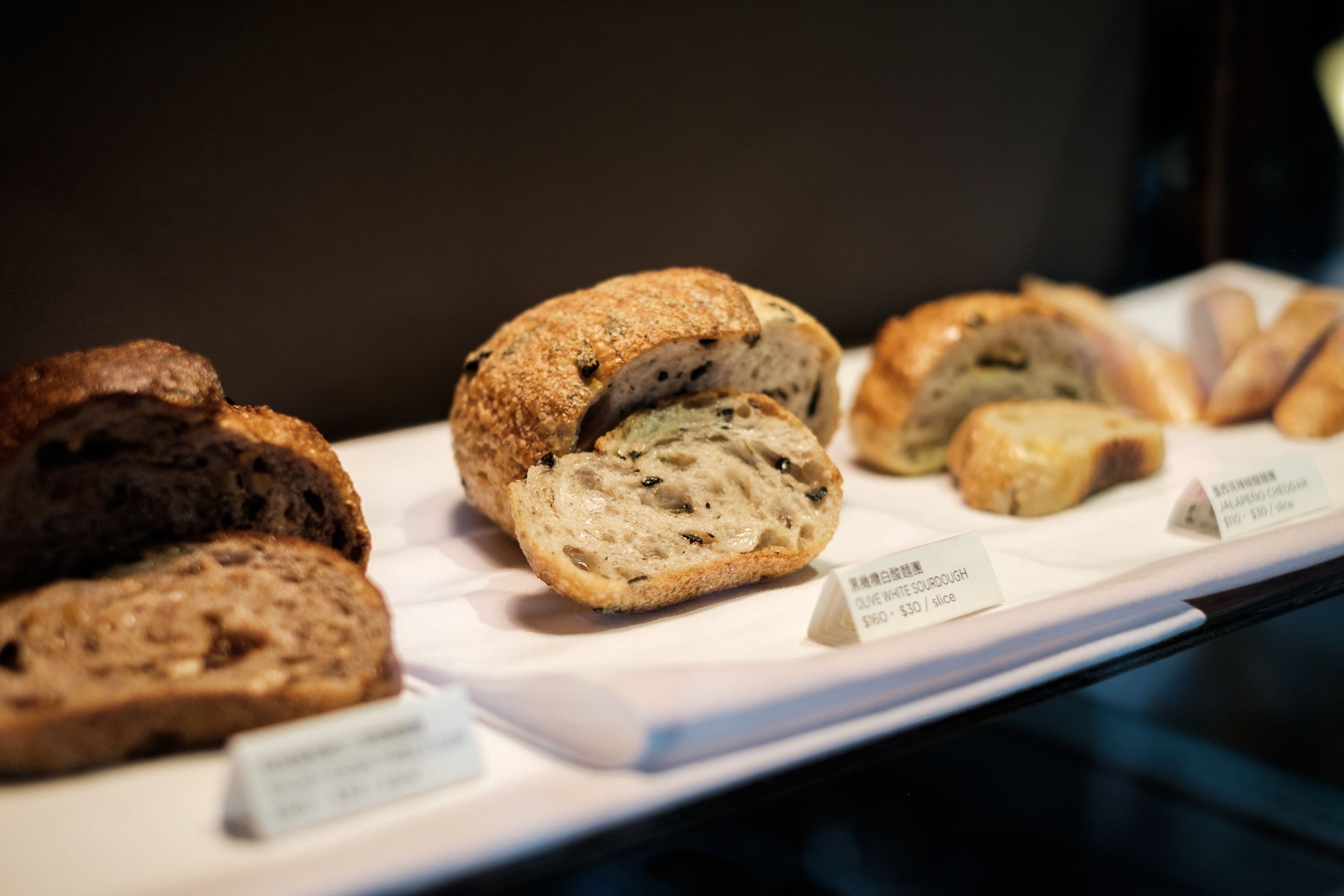 A display of various bread types with labels indicating names and prices.