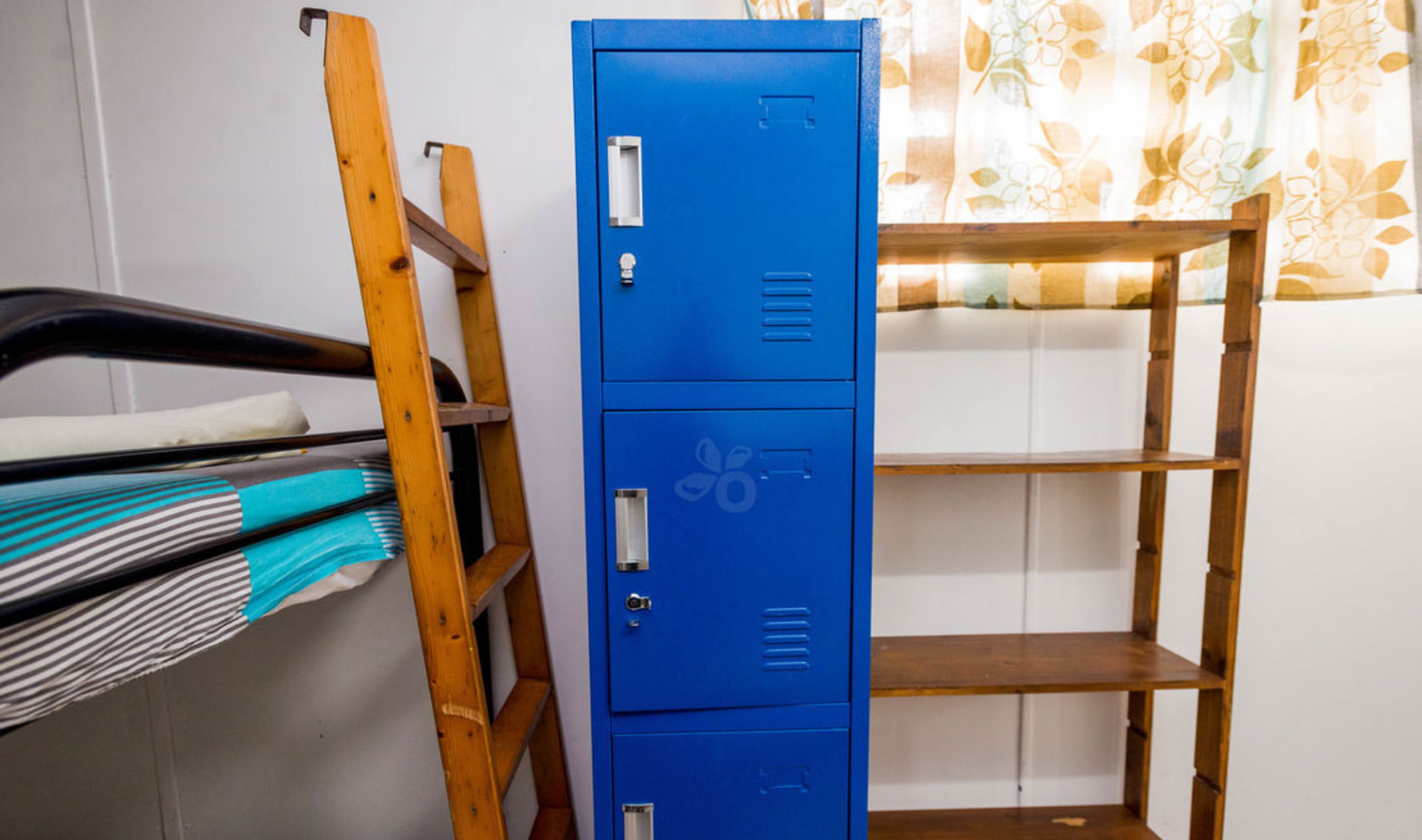 Ein Zimmer mit blauem Aktenschrank, einer Holzleiter und einem Holzregal.