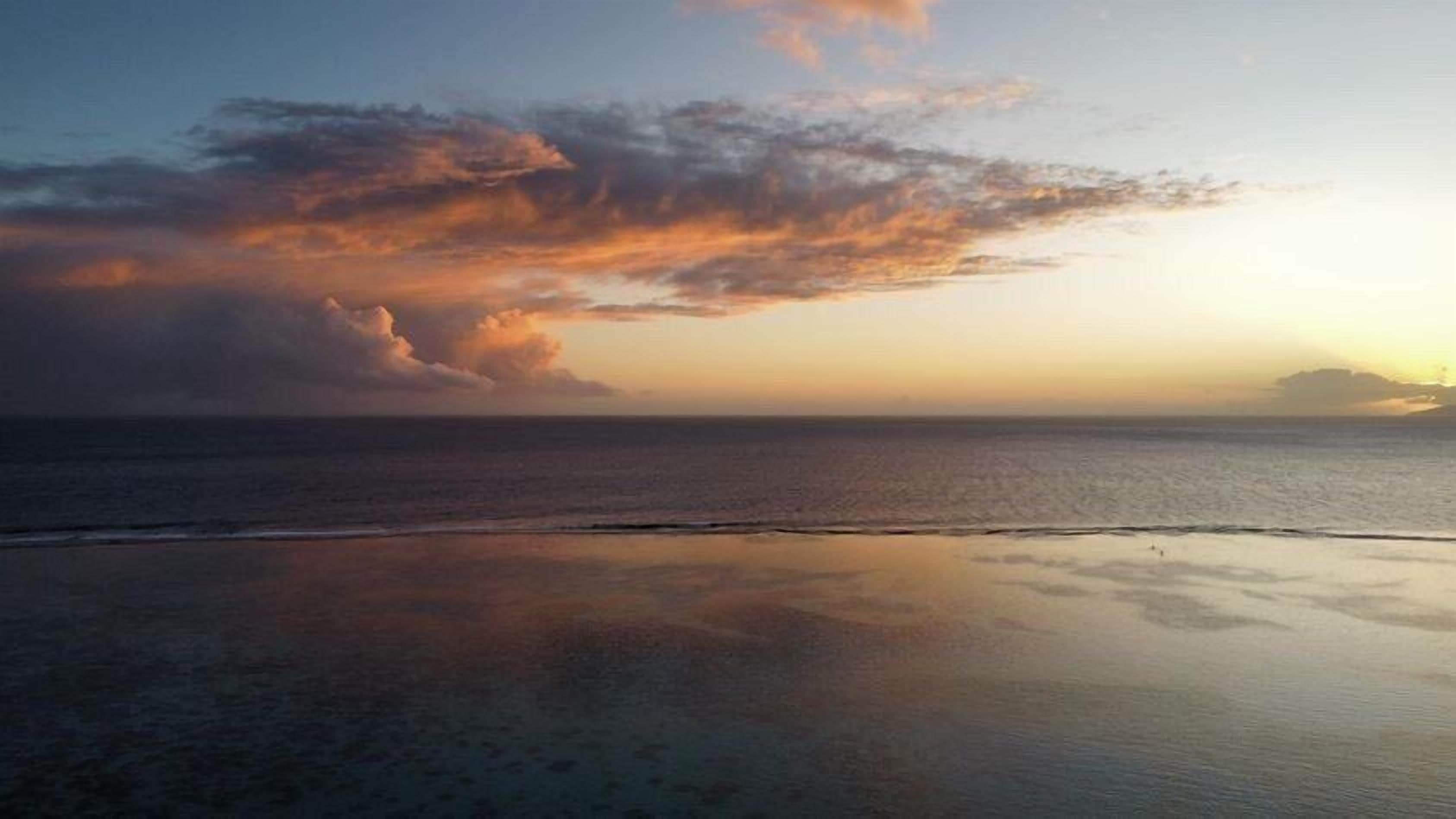 Une plage aux eaux calmes où le ciel se reflète.