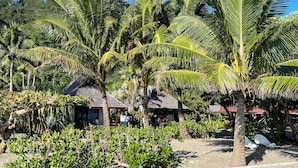 A tropical resort with palm trees, a beach, and a small building with a red roof. - Punatea Village (Taiarapu-Est)