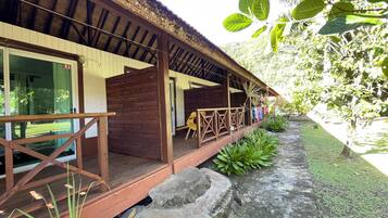 A wooden building with a covered porch, a stone pathway, and lush greenery.
