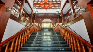 A grand staircase with wooden balusters and a glass railing, leading to an arched entrance. - Nui Than Tai Ebisu Onsen Resort (Da Nang)